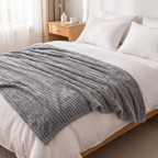Grey milk fleece blanket on a bed