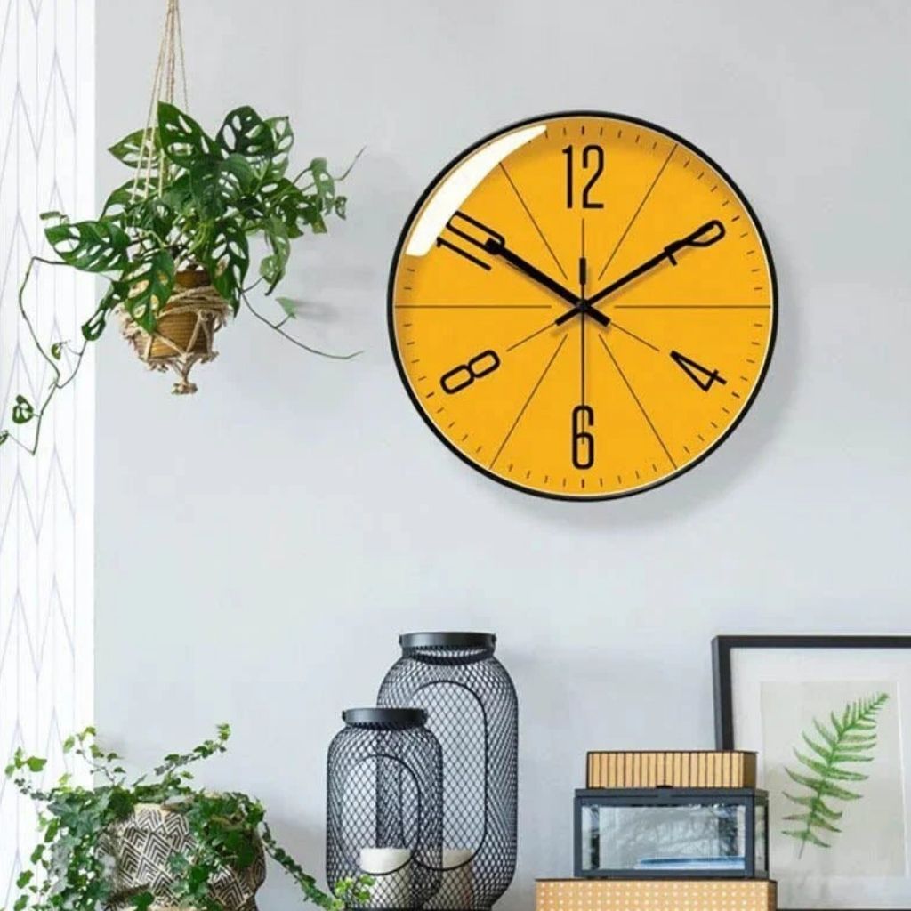 Modern Nordic wall clock with orange face hanging beside plants